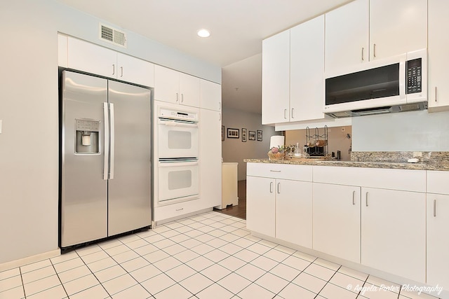 kitchen with white appliances, white cabinets, and stone countertops