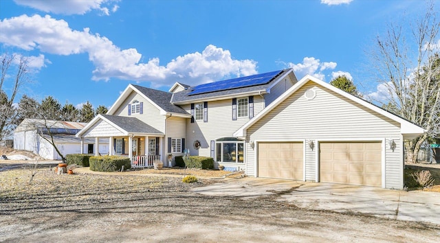 view of front facade with an attached garage, covered porch, roof mounted solar panels, and concrete driveway