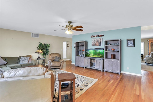 living room featuring visible vents, ceiling fan, baseboards, and wood finished floors