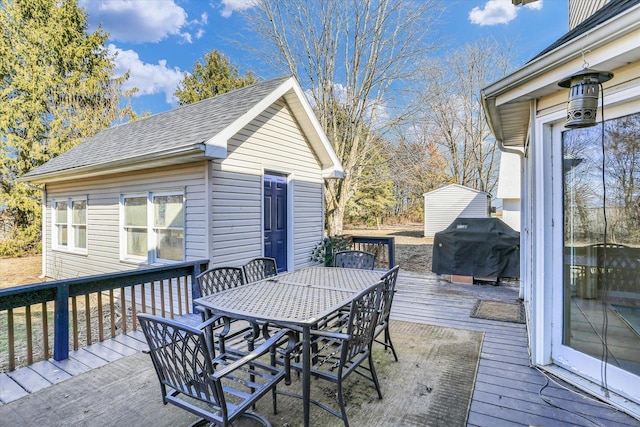 wooden deck featuring outdoor dining space, an outdoor structure, and grilling area