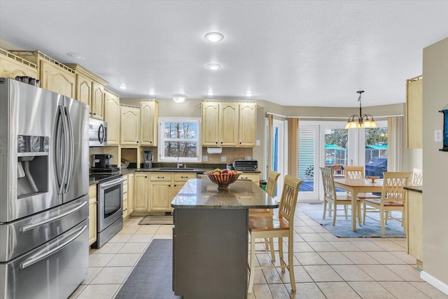 kitchen with light tile patterned floors, stainless steel appliances, light brown cabinetry, and plenty of natural light