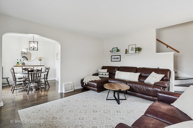 living area with arched walkways, baseboards, wood finished floors, and an inviting chandelier