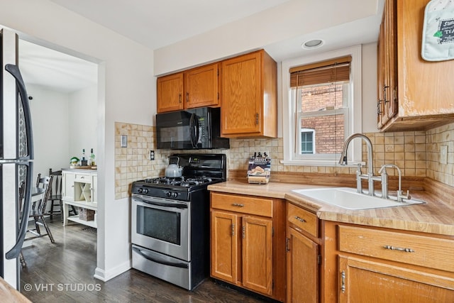 kitchen with light countertops, fridge, black microwave, a sink, and gas stove