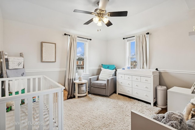 bedroom featuring ceiling fan and a crib