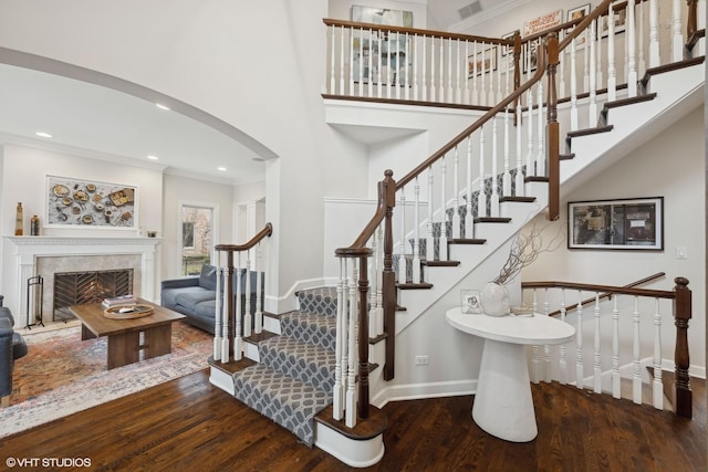 stairs featuring arched walkways, baseboards, wood finished floors, and crown molding