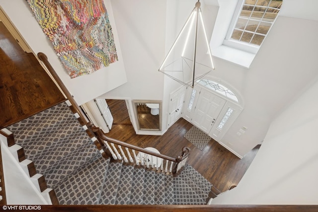 entrance foyer with wood finished floors, a towering ceiling, and stairs