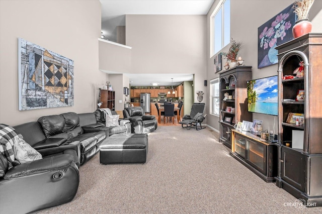 living room featuring a wealth of natural light, carpet flooring, and a towering ceiling