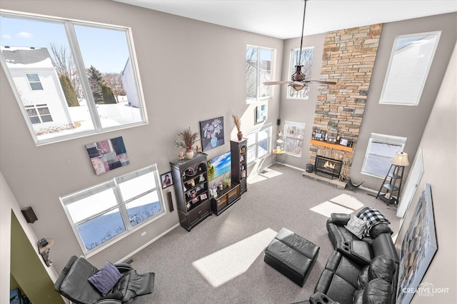 living room with ceiling fan, a healthy amount of sunlight, a high ceiling, and a stone fireplace