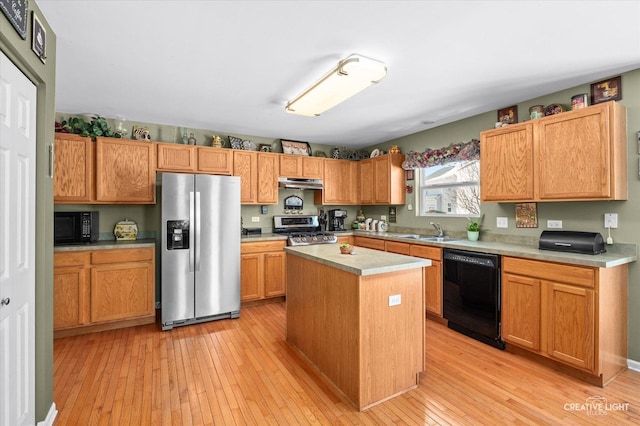 kitchen with black appliances, light hardwood / wood-style flooring, a kitchen island, and sink