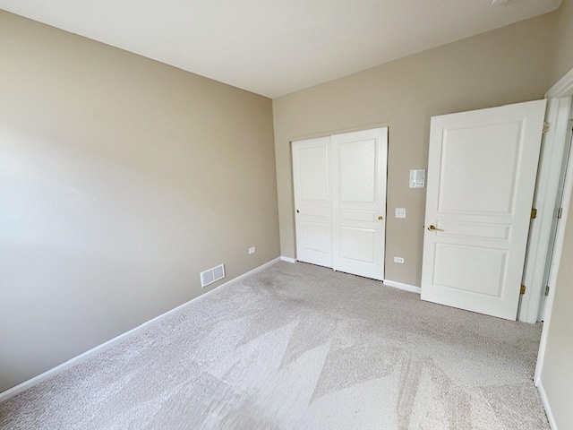 unfurnished bedroom featuring light carpet and a closet