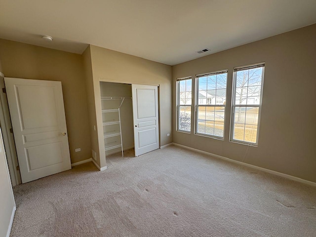 unfurnished bedroom featuring light carpet and a closet