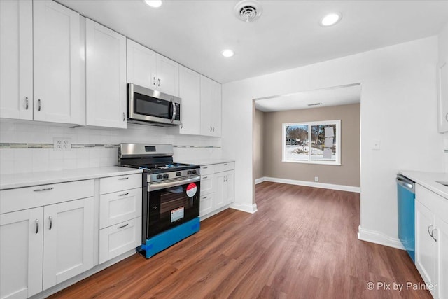 kitchen with white cabinetry, dark wood-type flooring, tasteful backsplash, and stainless steel appliances