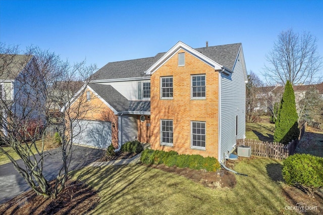 traditional-style home with fence, an attached garage, central AC, aphalt driveway, and brick siding