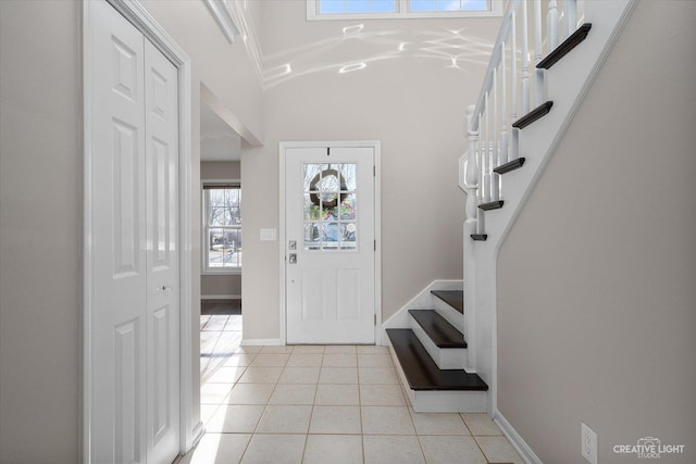 foyer entrance featuring stairway, light tile patterned floors, and baseboards