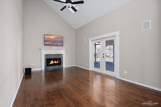 unfurnished living room featuring high vaulted ceiling, hardwood / wood-style flooring, french doors, a fireplace, and baseboards