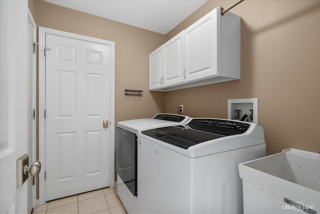 laundry area featuring cabinet space, light tile patterned floors, washer and dryer, and a sink