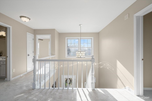 hallway featuring visible vents, an upstairs landing, carpet, and baseboards