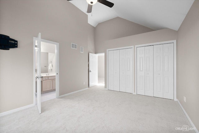 unfurnished bedroom with visible vents, baseboards, multiple closets, light colored carpet, and ensuite bath