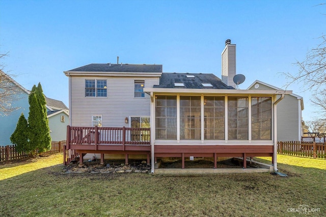 rear view of property with a sunroom, a chimney, a fenced backyard, a deck, and a yard