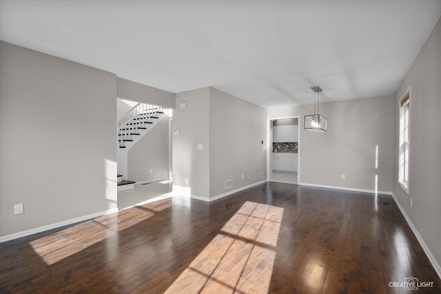 interior space with stairway, wood finished floors, visible vents, baseboards, and a notable chandelier