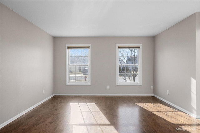 unfurnished room with plenty of natural light, wood finished floors, and baseboards