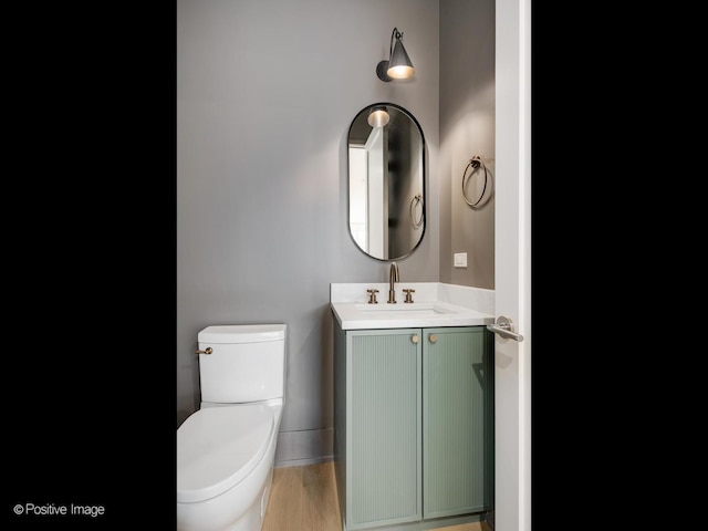 bathroom featuring wood-type flooring, vanity, and toilet