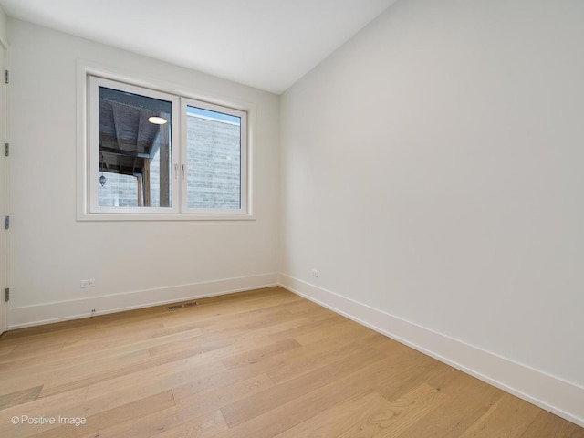 spare room with light hardwood / wood-style flooring and vaulted ceiling