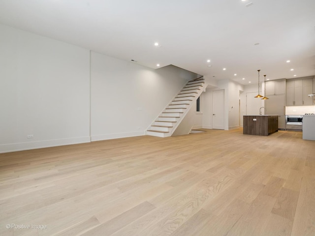 unfurnished living room with light hardwood / wood-style flooring and sink