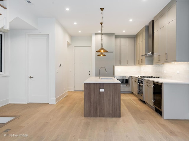 kitchen featuring a center island with sink, sink, beverage cooler, pendant lighting, and wall chimney exhaust hood