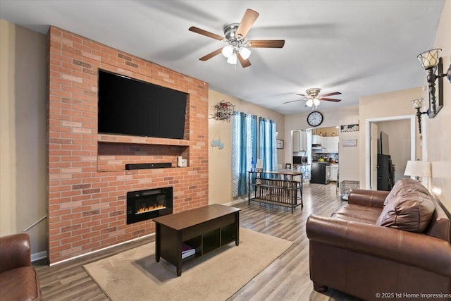 living room with a fireplace, light wood-style flooring, and a ceiling fan