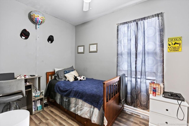 bedroom with wood finished floors, visible vents, and a ceiling fan