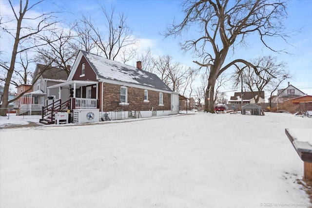 view of snow covered exterior featuring a chimney and brick siding