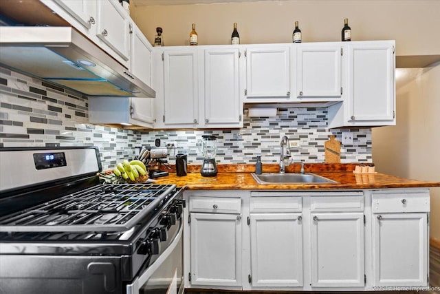 kitchen with under cabinet range hood, a sink, white cabinets, stainless steel gas range, and tasteful backsplash