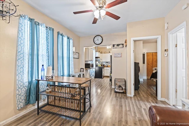 dining area with ceiling fan, light wood finished floors, and baseboards