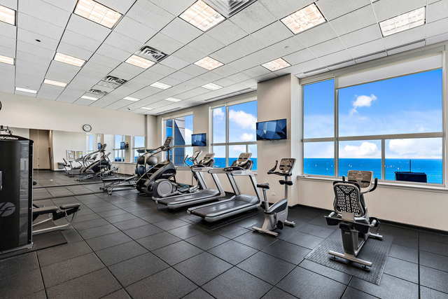 workout area featuring water heater, visible vents, and a drop ceiling