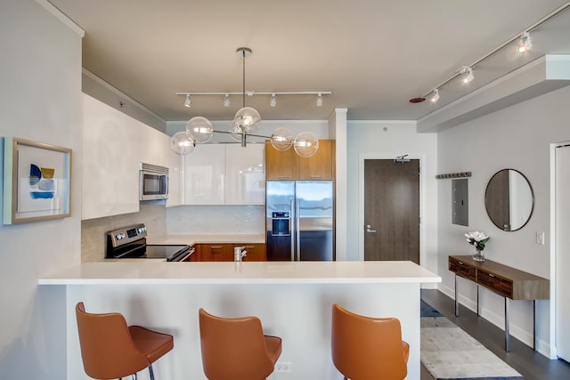 kitchen with appliances with stainless steel finishes, brown cabinets, a breakfast bar area, a peninsula, and light countertops