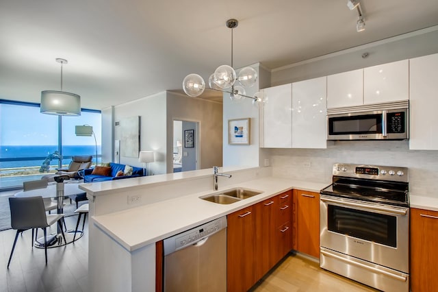 kitchen featuring white cabinets, appliances with stainless steel finishes, brown cabinets, light countertops, and pendant lighting