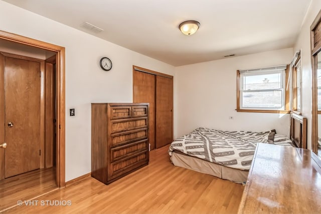 bedroom with light wood-style floors, a closet, and visible vents