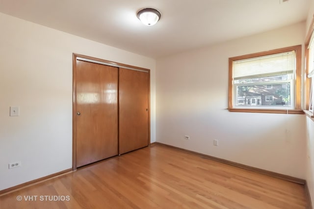 unfurnished bedroom featuring light wood-type flooring, a closet, and baseboards