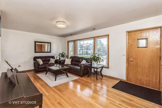 living room featuring baseboards, visible vents, and wood finished floors