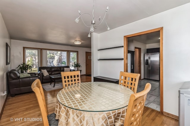 dining area with washer / dryer, light wood-type flooring, and an inviting chandelier