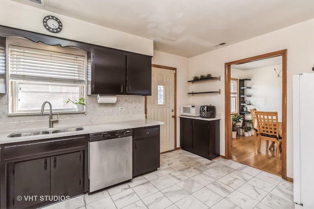 kitchen featuring marble finish floor, light countertops, freestanding refrigerator, a sink, and dishwasher