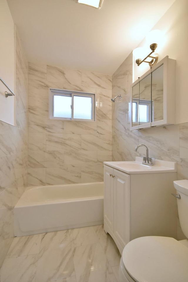 full bathroom featuring tile walls, tiled shower / bath combo, vanity, and toilet