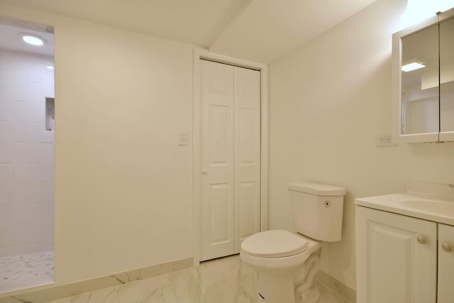 bathroom featuring toilet, vanity, and tiled shower