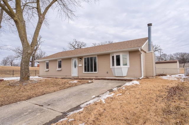 ranch-style house with roof with shingles and fence