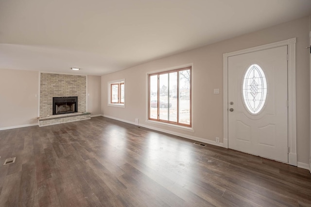 entrance foyer with dark wood-style floors, baseboards, a fireplace, and visible vents