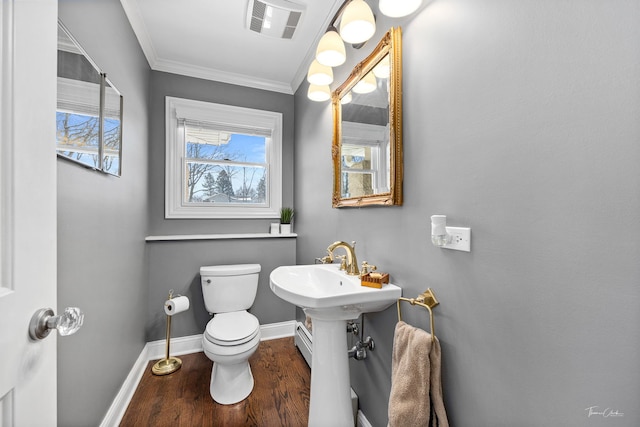 half bath with toilet, a wealth of natural light, visible vents, and crown molding