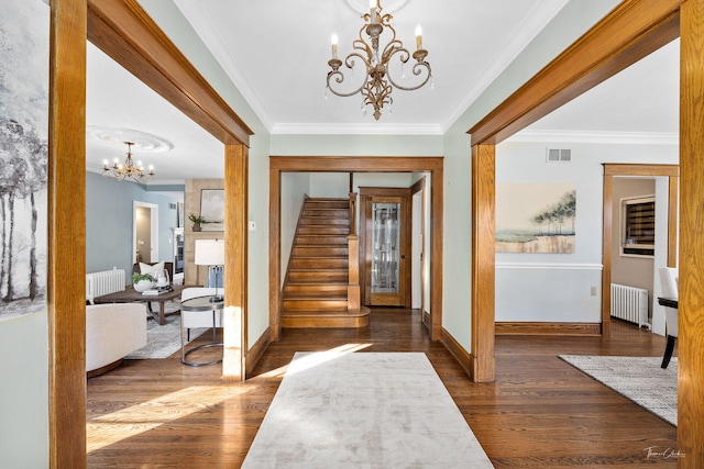 foyer entrance with visible vents, radiator heating unit, stairs, crown molding, and a notable chandelier