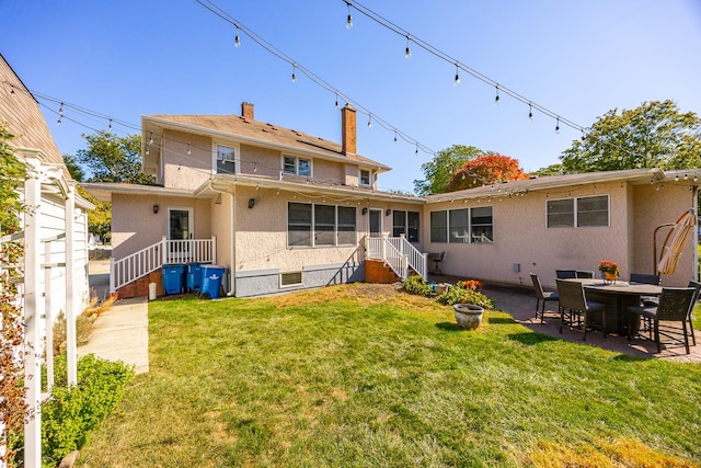 rear view of house featuring a lawn, a patio area, and stucco siding