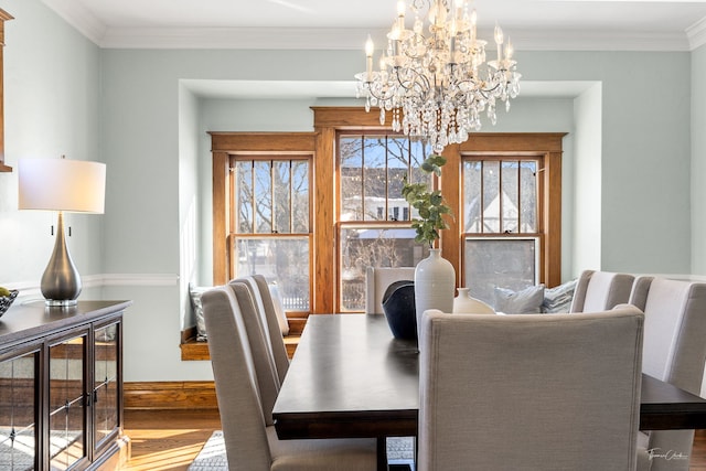 dining room with baseboards, ornamental molding, wood finished floors, and a notable chandelier